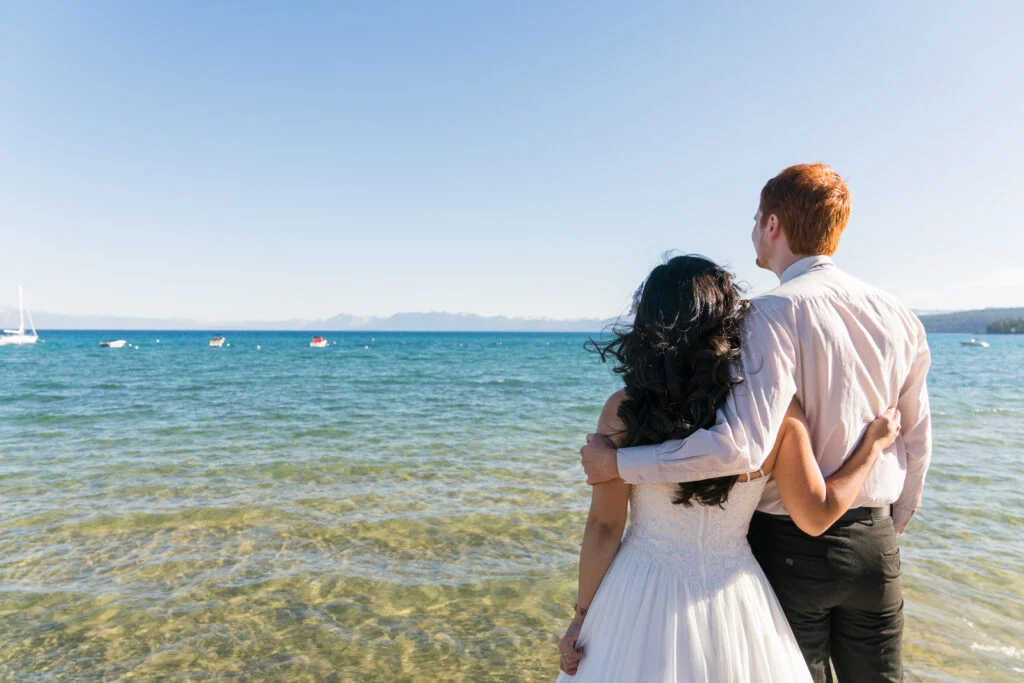 lake tahoe elopement couple looking out over the water and hugging