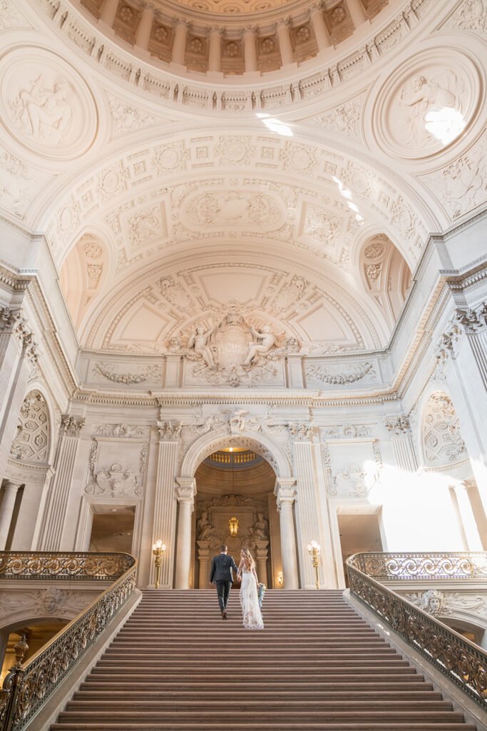 Bride and groom walk up Grand Staircase at SF City Hall.