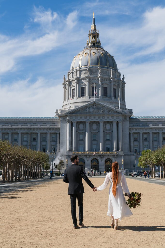 Bride and groom walking outside toward San Francisco City Hall.