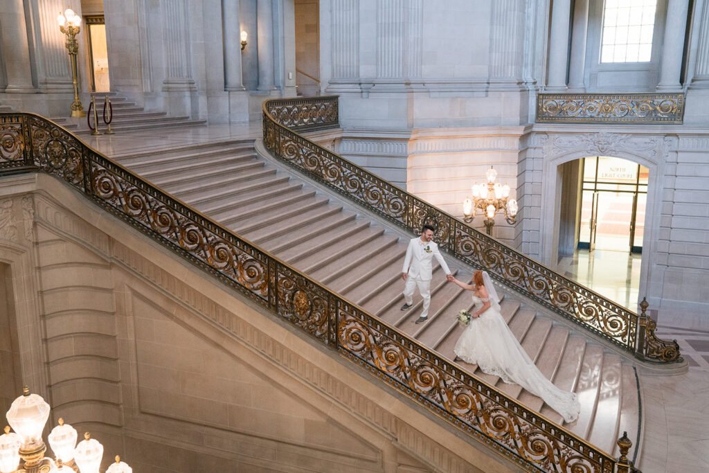 Bride and groom on grand staircase at San Francisco City Hall.